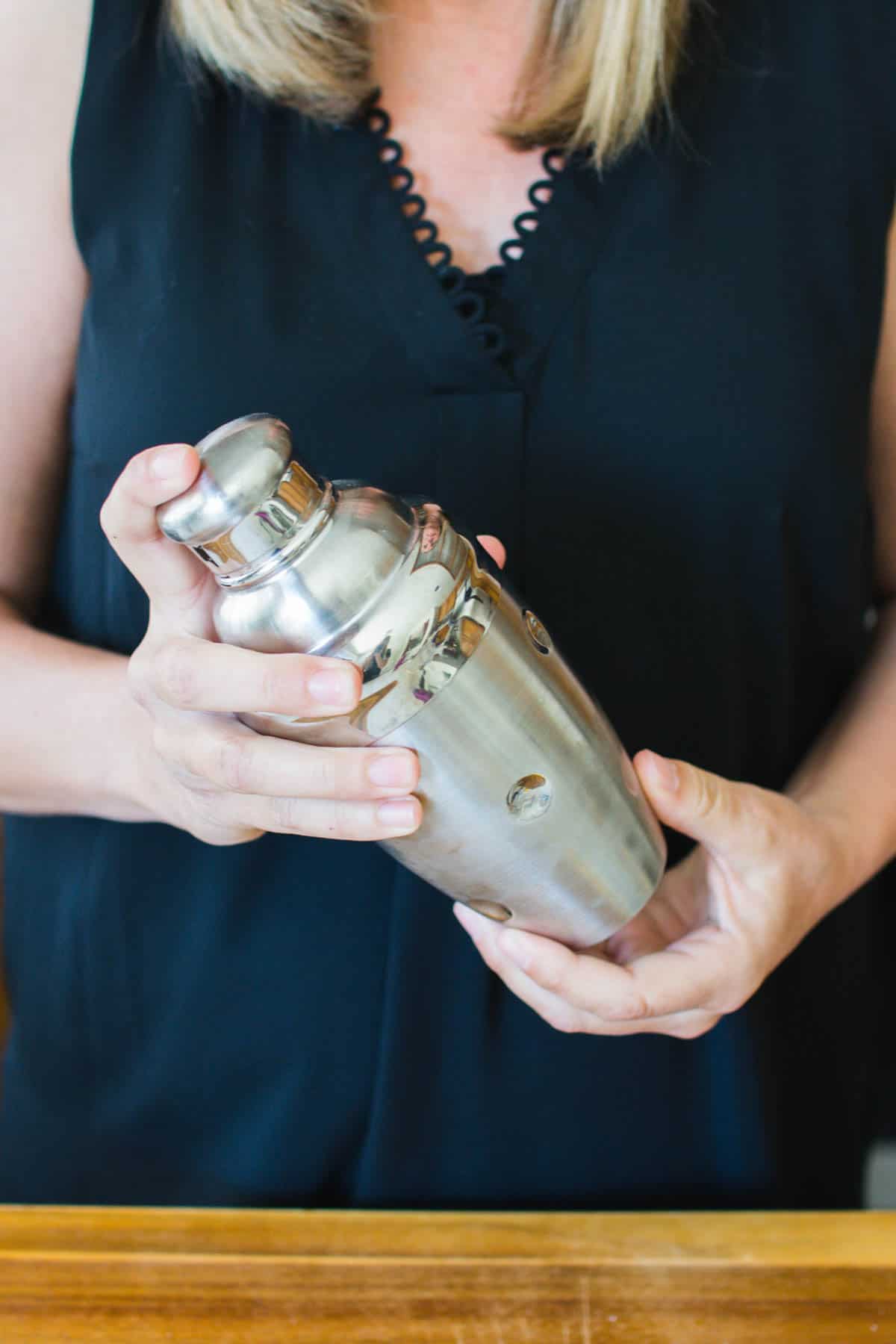 Woman shaking a cocktail shaker full of ingredients.