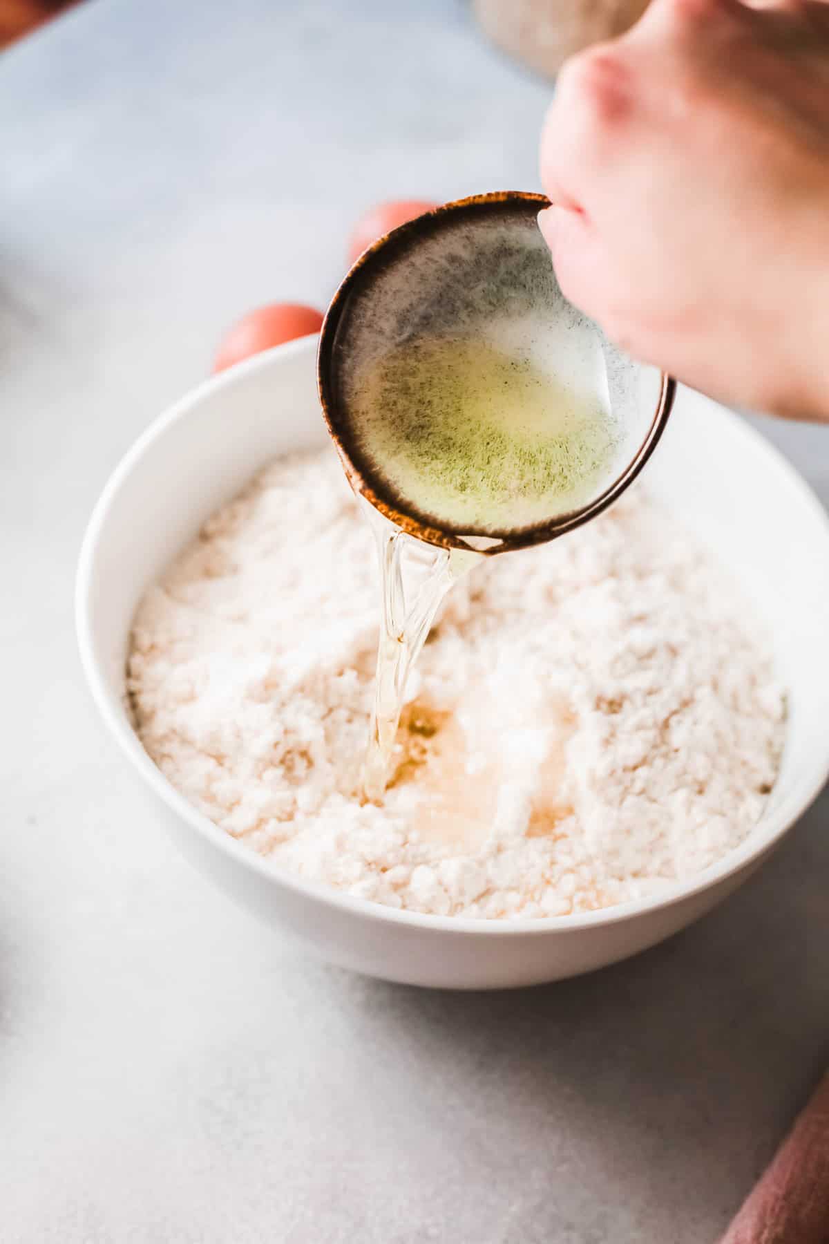 A hand pouring a small bowl of oil into a bowl with cake mix. 