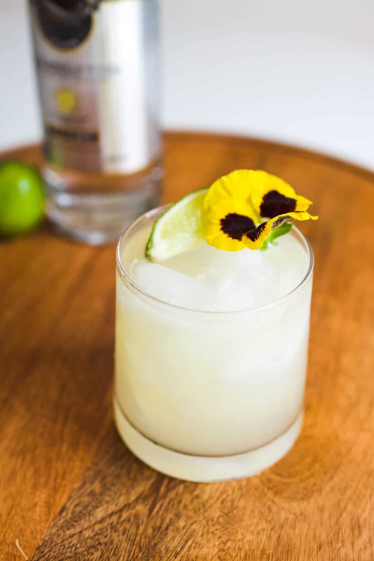 A Vodka Margarita on a counter with a flower and lime garnish.