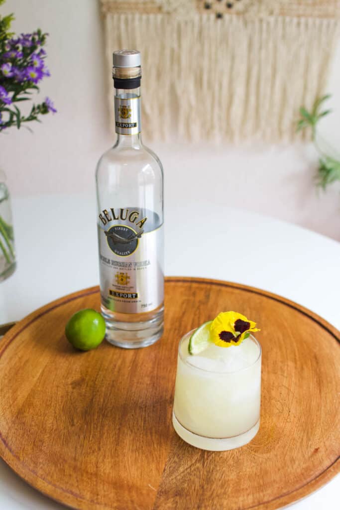 A bottle of vodka on a tray next to a glass with a vodka margarita.