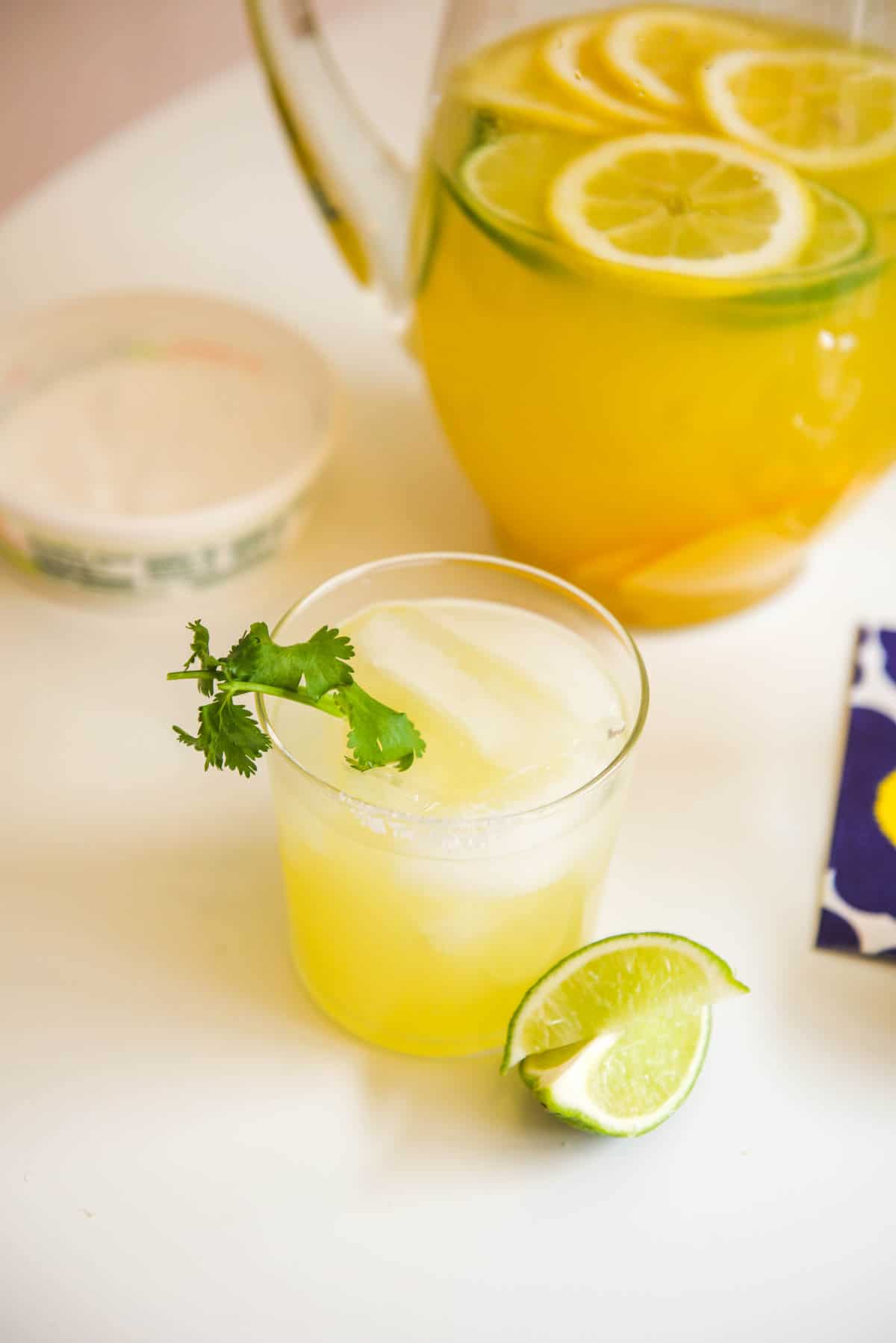 A cocktail glass with ice and a serving of Margarita Sangria with sprig of cilantro. 