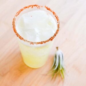 A Cucumber Margarita with Tajin rim on a table.