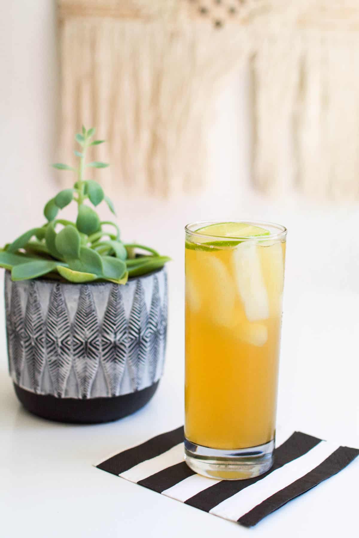 A Dark and Stormy cocktail in a tall glass on a black and white striped napkin.