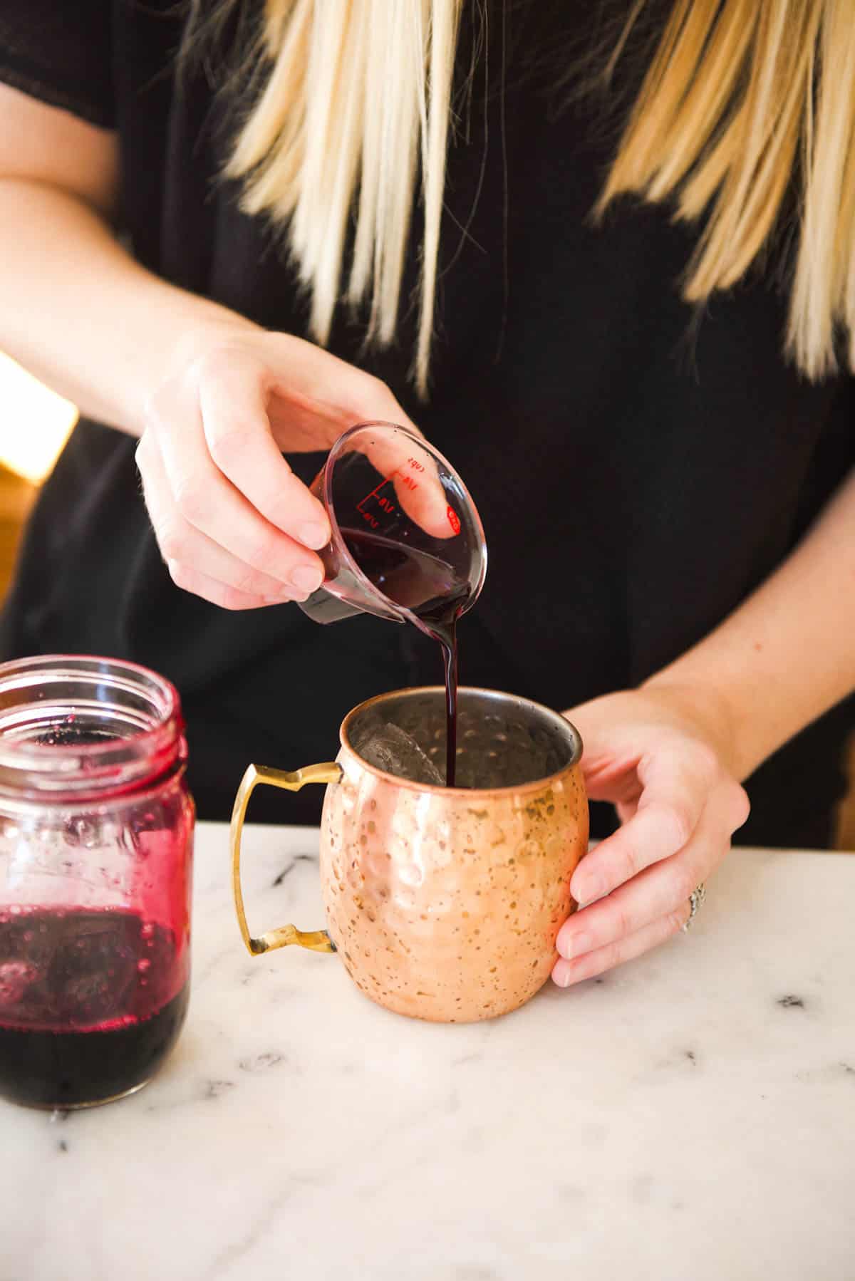 Pouring the the blueberry syrup to make the Blueberry Mule recipe. 