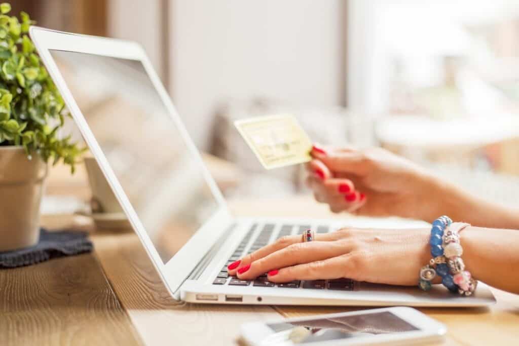 A woman holding a credit card and shopping on Macys.com for their Black Friday in July sale.