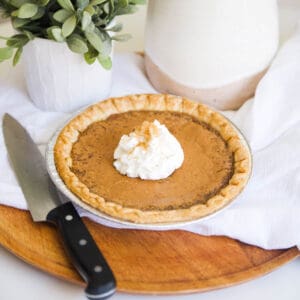 A whip cream topped Brown Sugar Pie next to a knife.