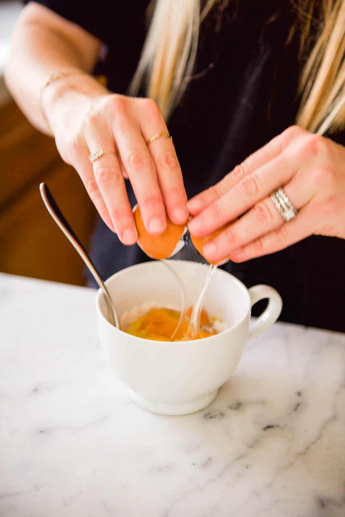 Adding eggs to a mug for a mug cake recipe.