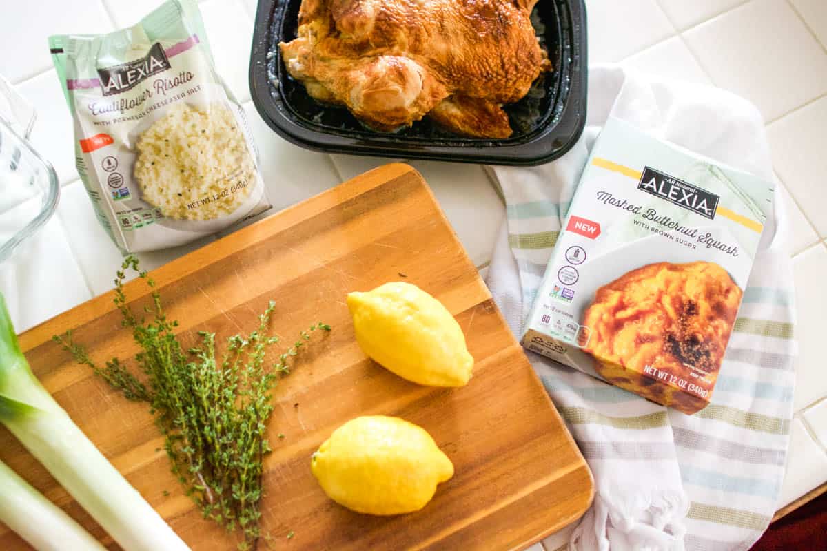 A cutting board with lemons, leeks and thyme next to boxes of Alexia side dishes.