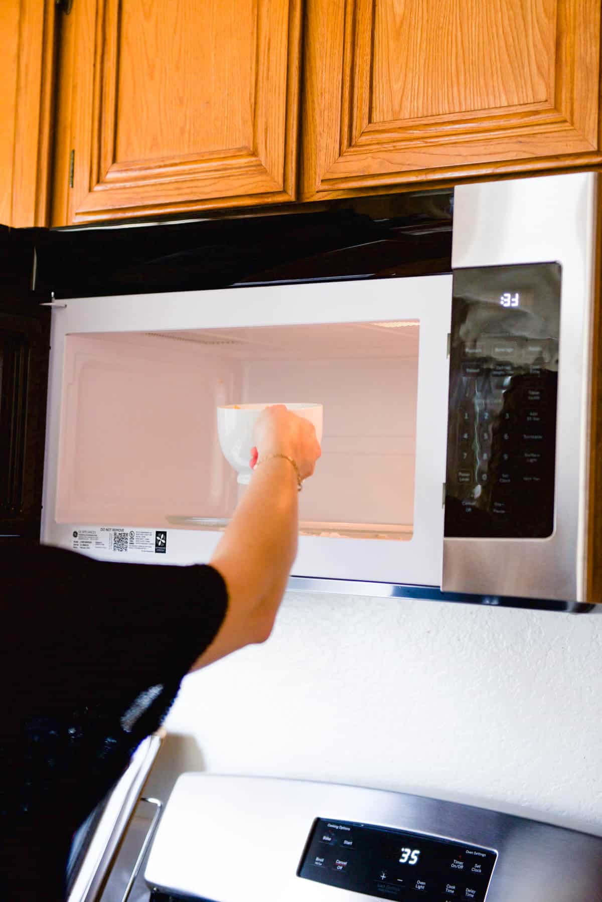 Woman putting mug cake in the microwave to bake.