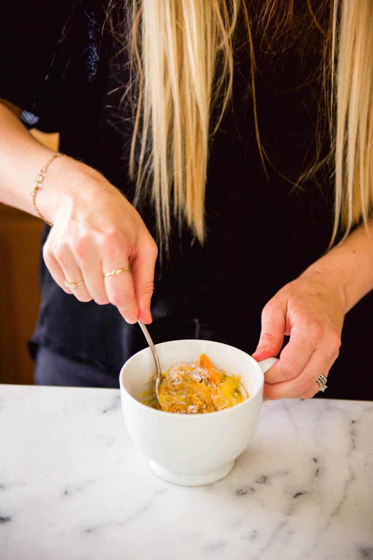 Woman mixing a mug cake with a fork.