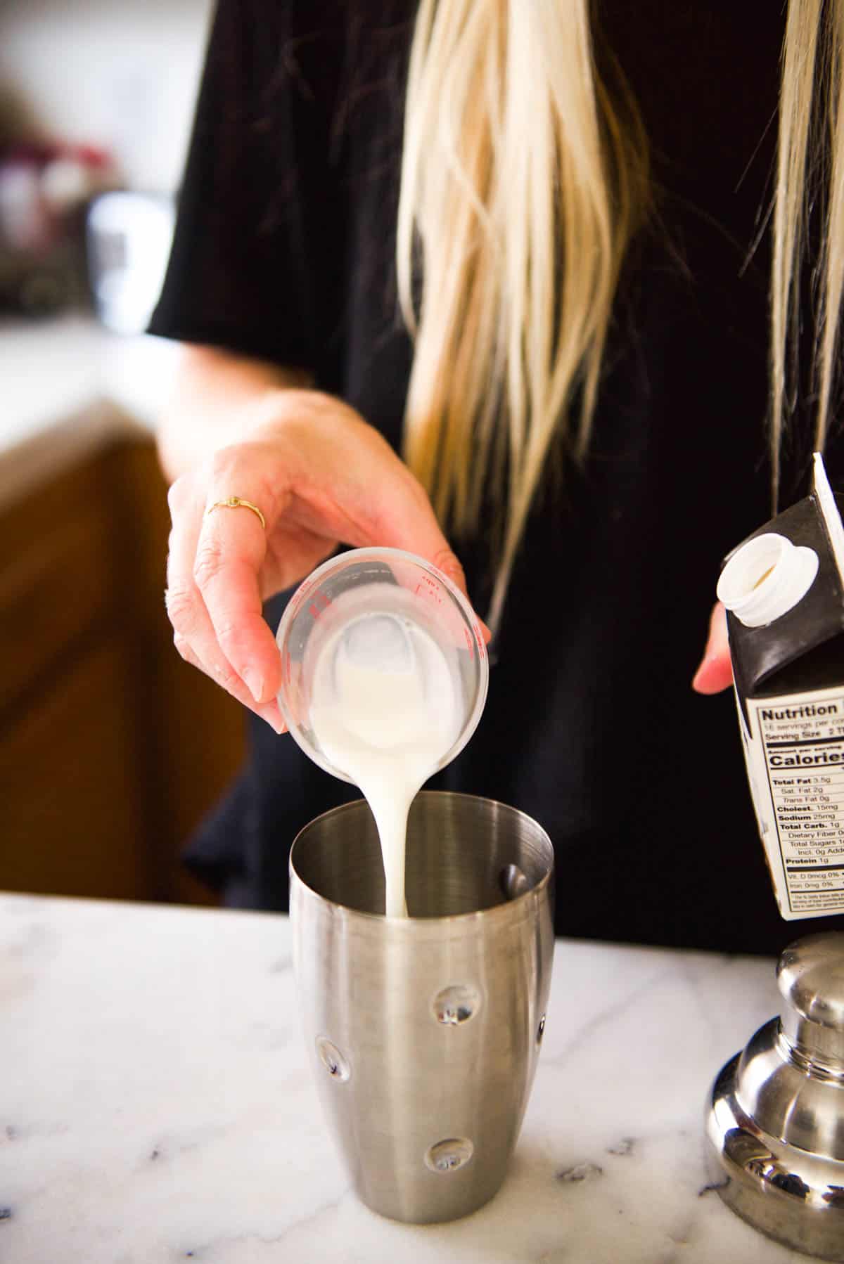 Adding half and half to a cocktail shaker.