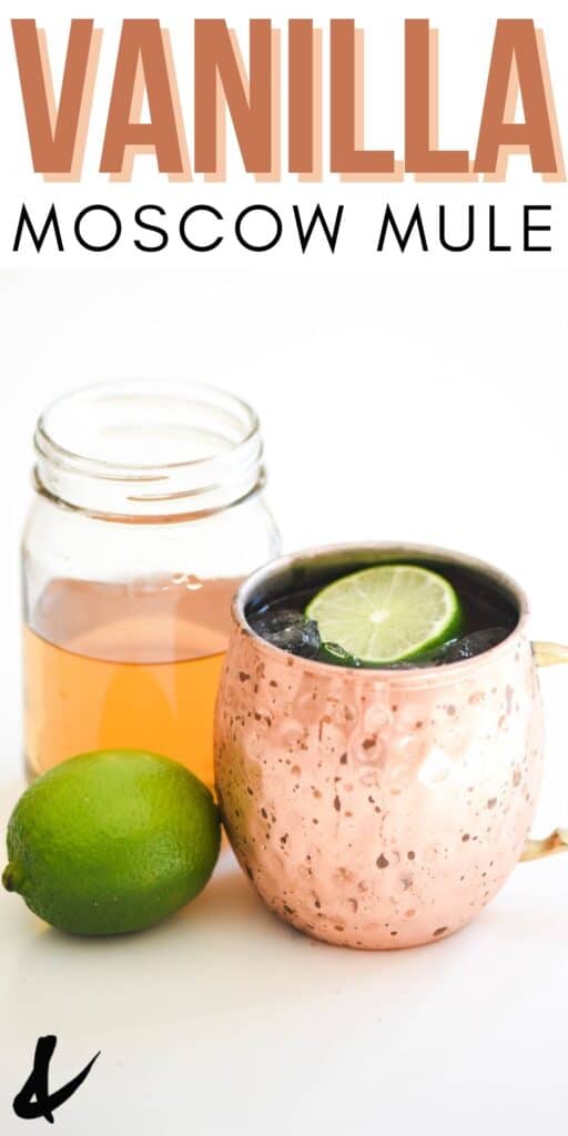 Close up of a copper mule mug on a table next to a fresh lime and a jar of simple syrup.