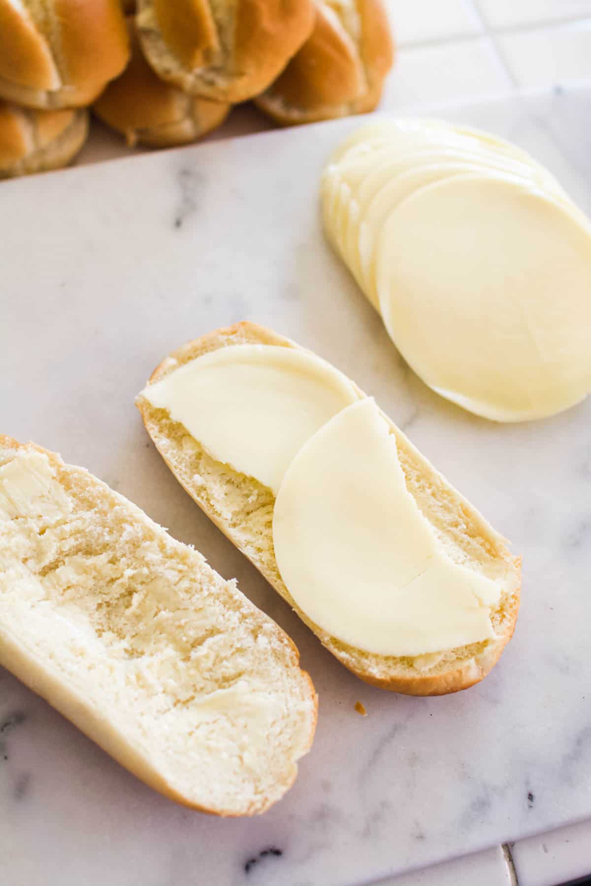 An open sandwich roll with provolone slices laying on one side.