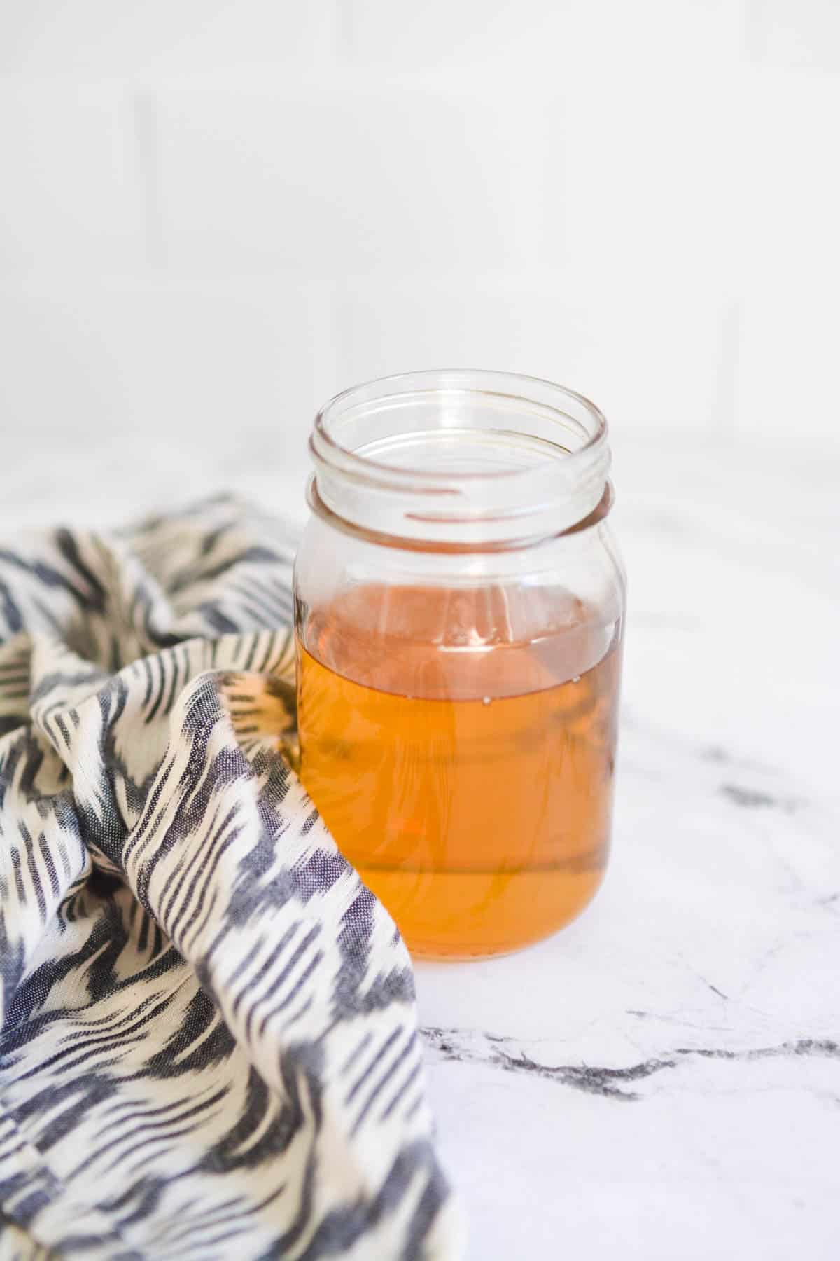 Homemade vanilla simple syrup in a glass jar on a table.