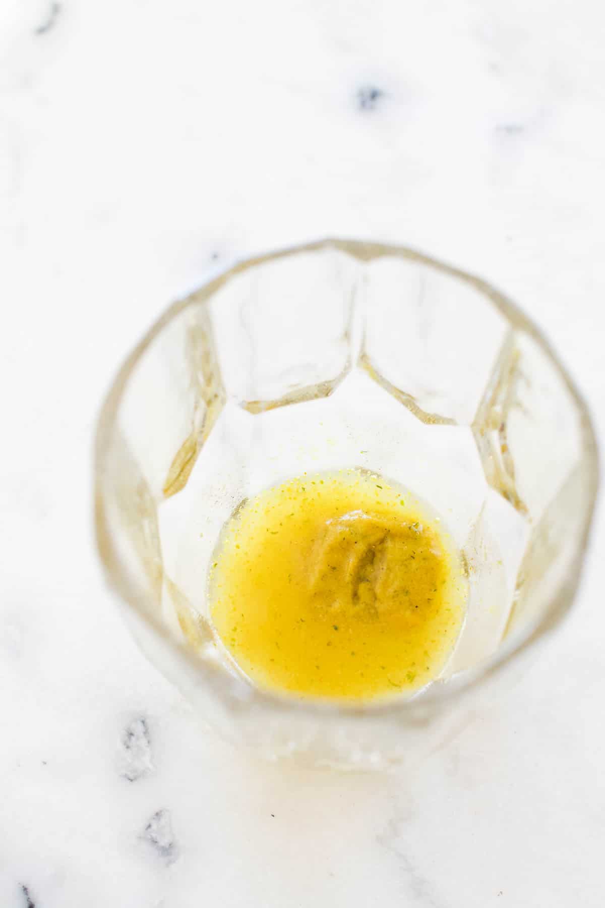 A chicken bouillon cube dissolving in water in a glass.