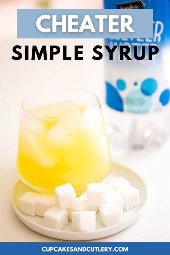 Yellow cocktail in a glass next to a pile of sugar cubes.