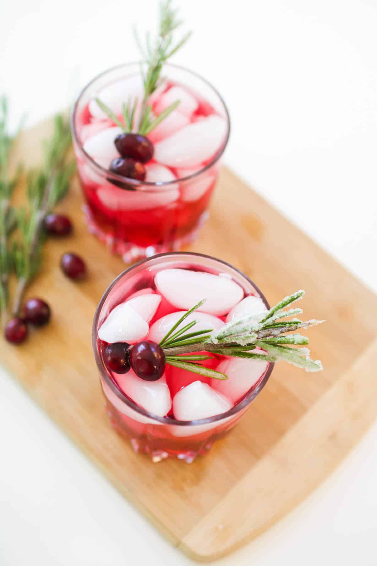 Overhead shot of two cocktail glasses with cranberry juice and vodka and garnished with rosemary and cranberries.