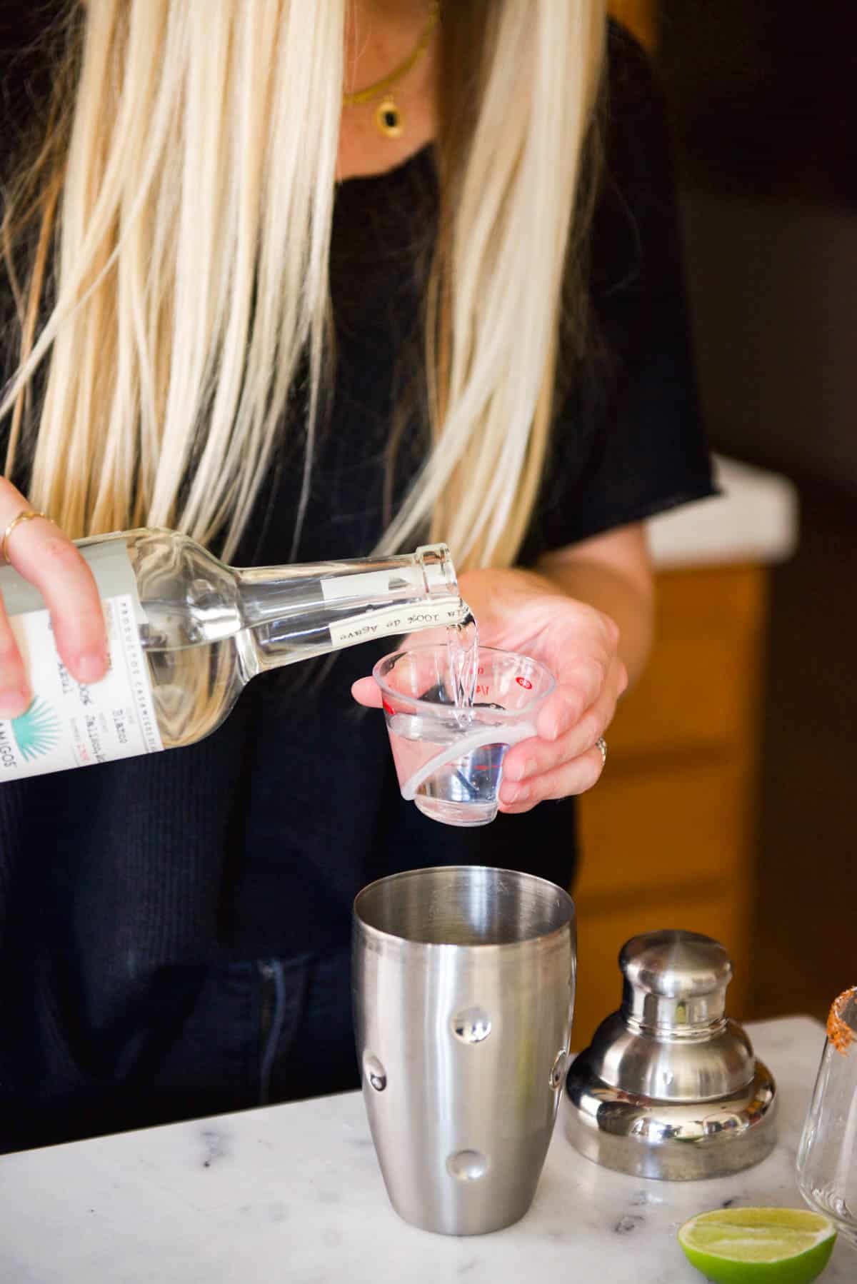 Woman measuring tequila in a jigger.