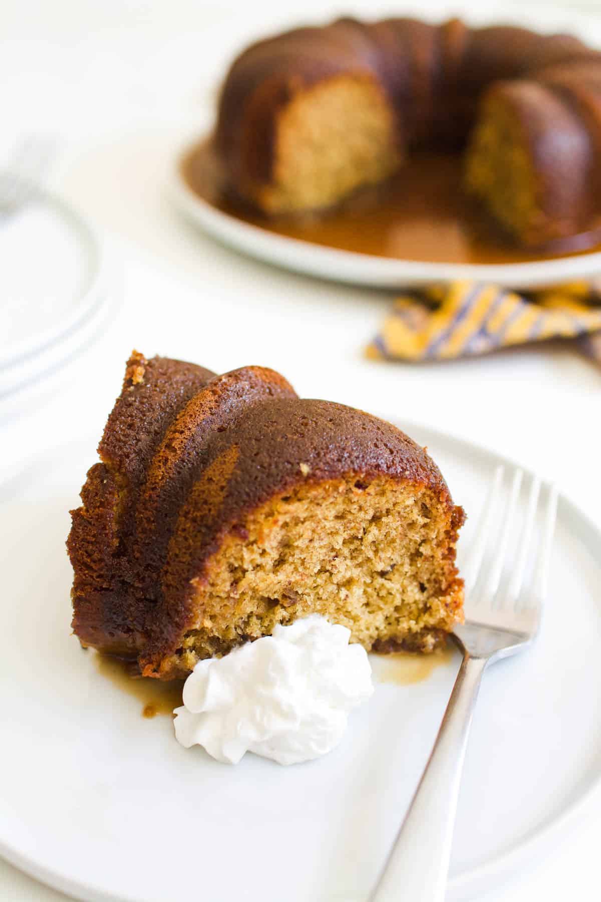 A piece of bourbon cake on a plate with whipped cream.