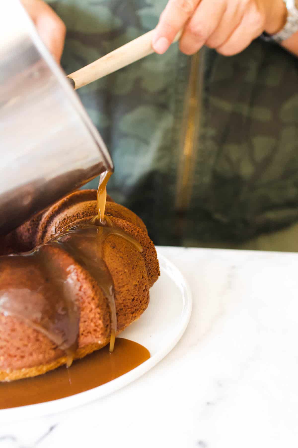 Woman pouring caramel over a bundt cake.