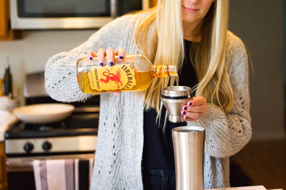 A woman measuring fireball in a cocktail shaker.