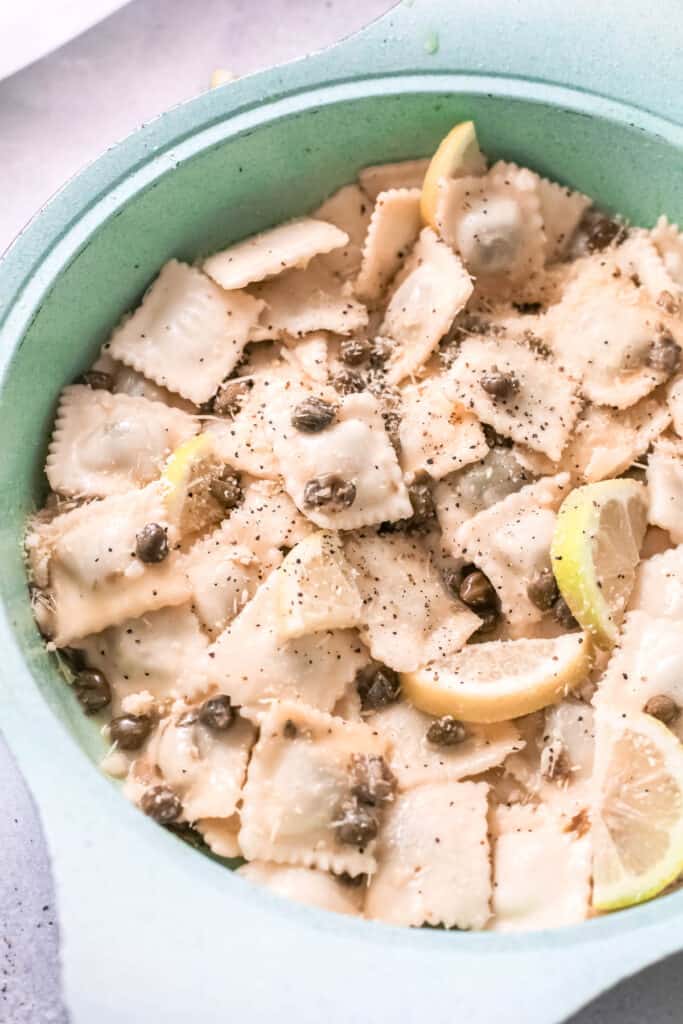 Close up of capers and lemon slices mixed with ravioli.