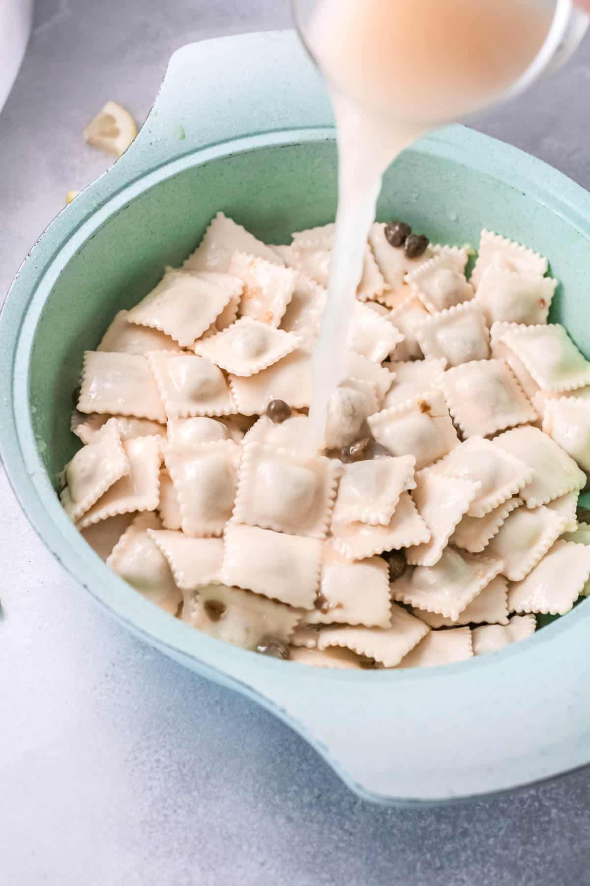 Bowl of ravioli with chicken stock being added.