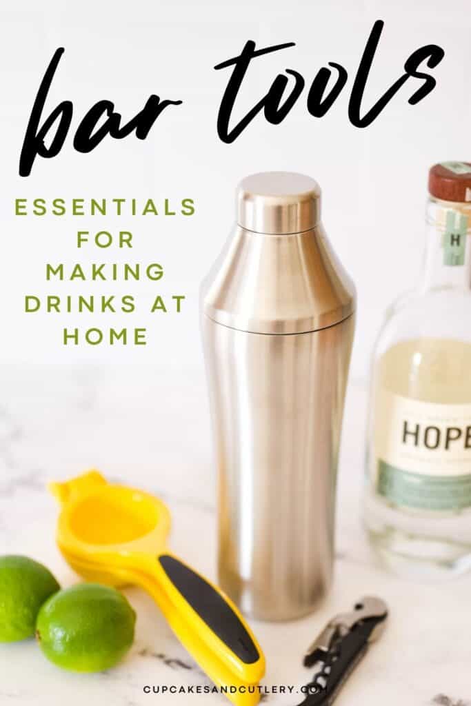 A cocktail shaker on a table next to some other essential bar tools.