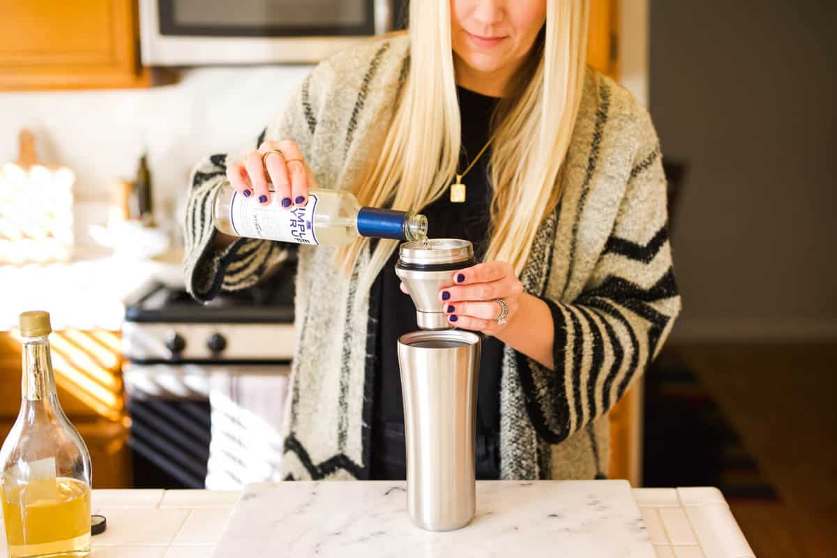 Woman measuring simple syrup for a cocktail.