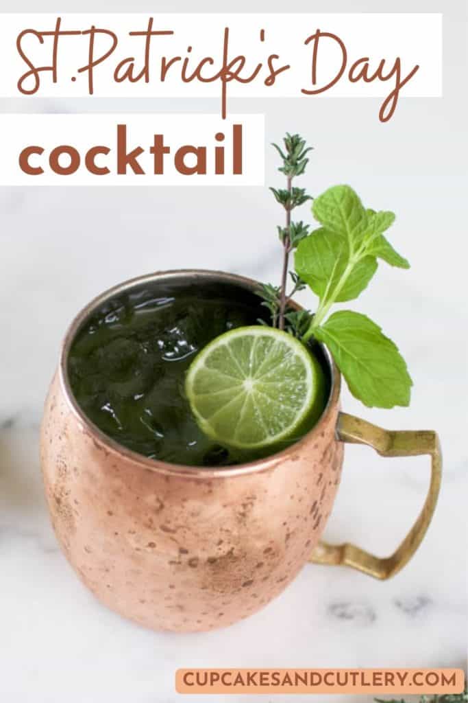 Text - St. Patrick's Day cocktail over an image of a copper mule mug with a green drink idea garnished with a lime wheel and fresh herbs.