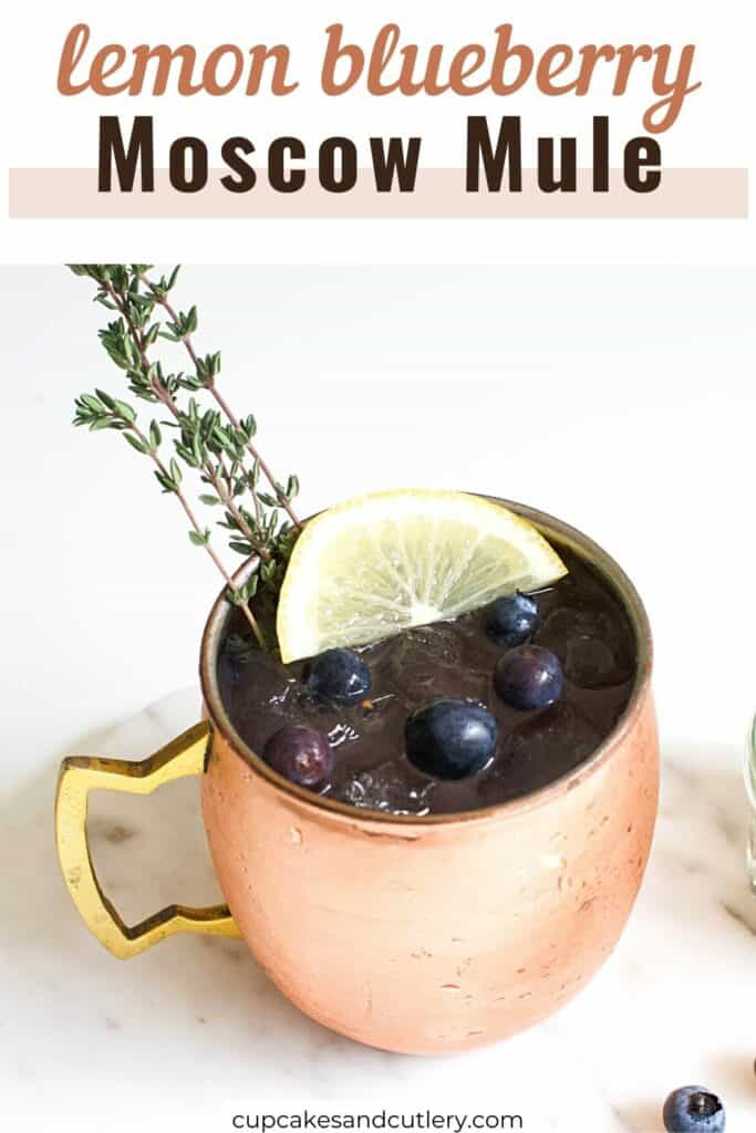 Text - lemon blueberry Moscow Mule with a copper Moscow Mule mug with a lemon blueberry cocktail topped with a wedge of lemon and fresh thyme.