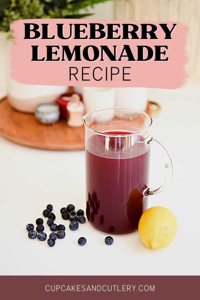 A pitcher of homemade blueberry lemonade on a table next to fresh lemon and blueberry.