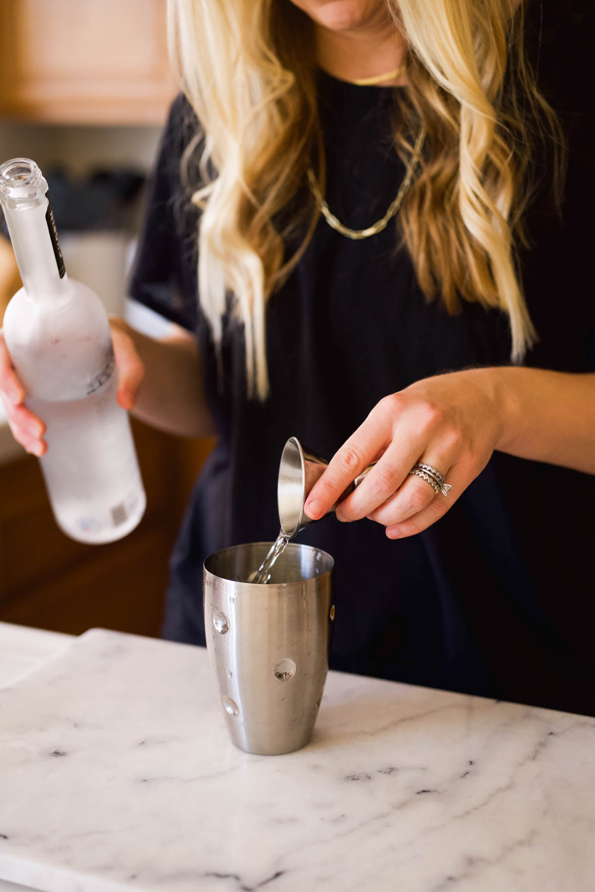 Woman adding vodka to a cocktail shaker.