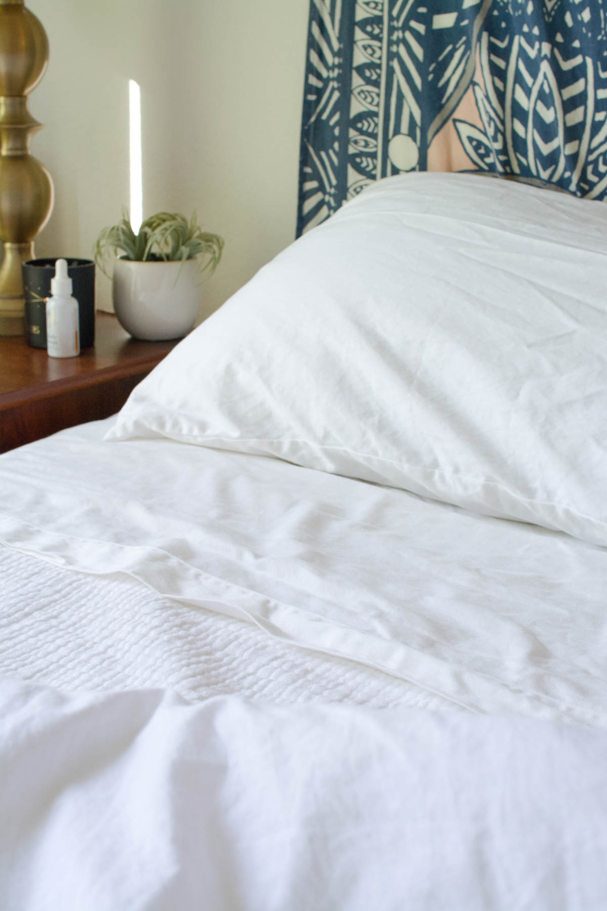 A bed in white sheets next to a night stand. 