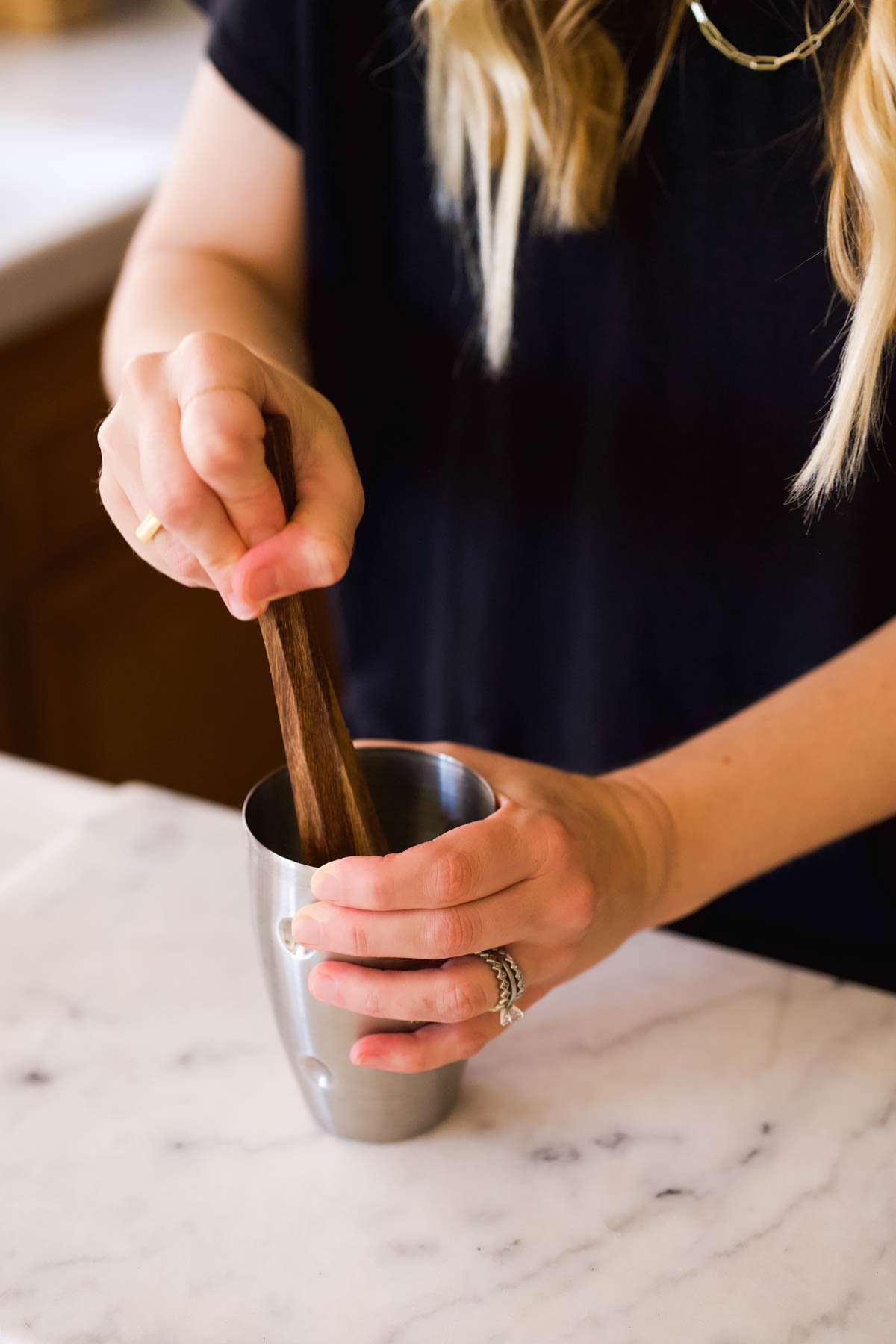 Woman using muddler in a cocktail shaker.