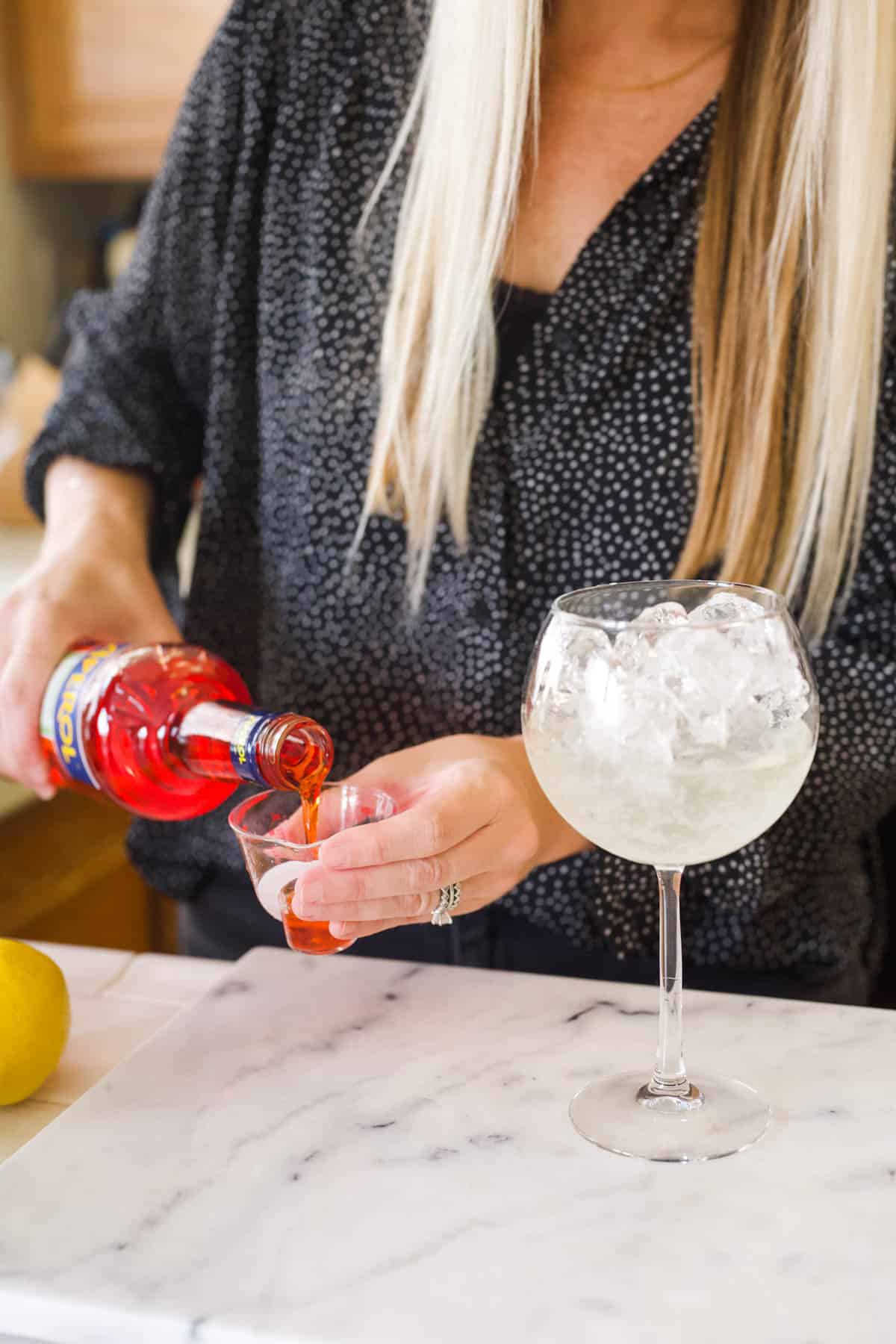 Measuring Aperol for a Watermelon Aperol Spritz.