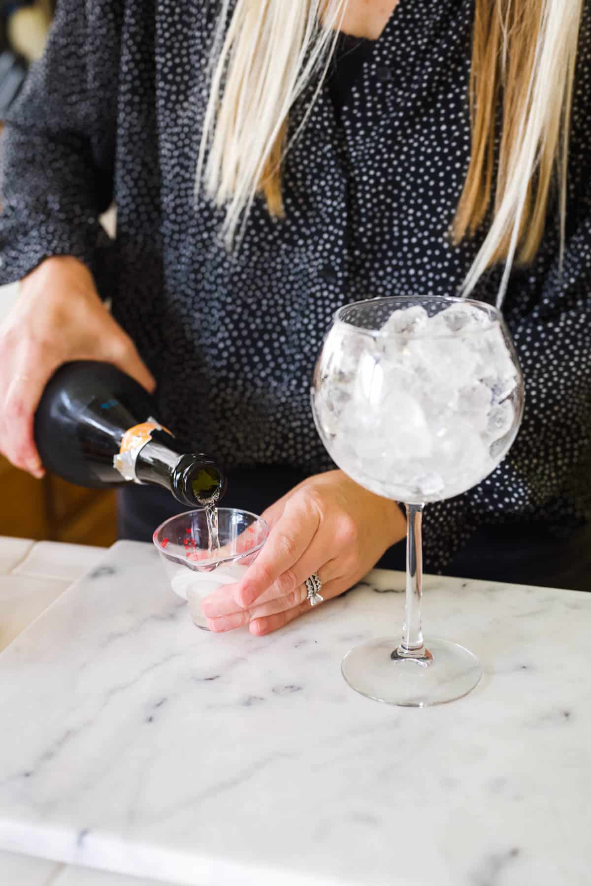 Measuring prosecco in a small measuring cup.