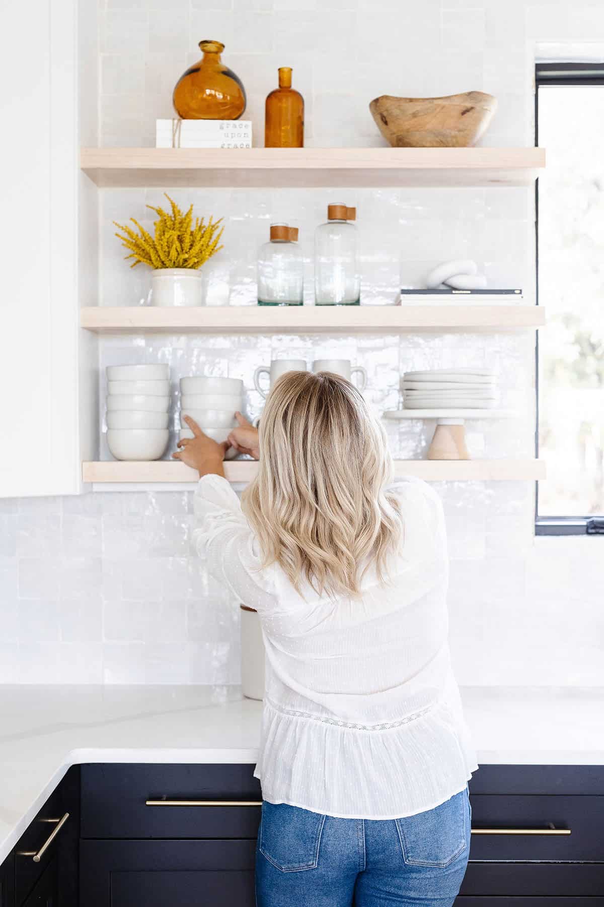 Woman putting dishes away in the cupboard.