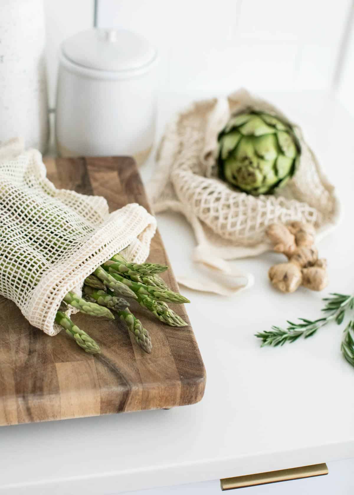 Fresh produce on a kitchen counter in reusable grocery bags.