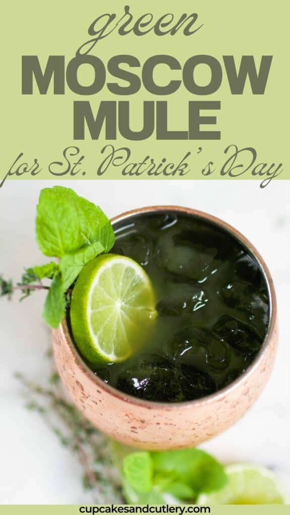 Text: Green Moscow mule for St. Patrick's Day with a copper mug garnished with lime and herbs.