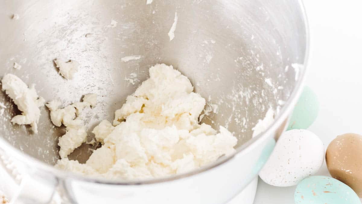 Cream cheese in the bowl of a stand mixer.