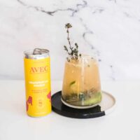 Grapefruit mocktail in a glass next to a can of Avec soda.