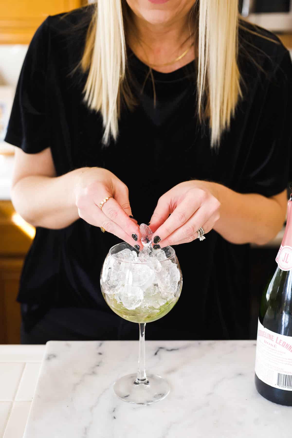 Woman adding ice to a spritz glass.