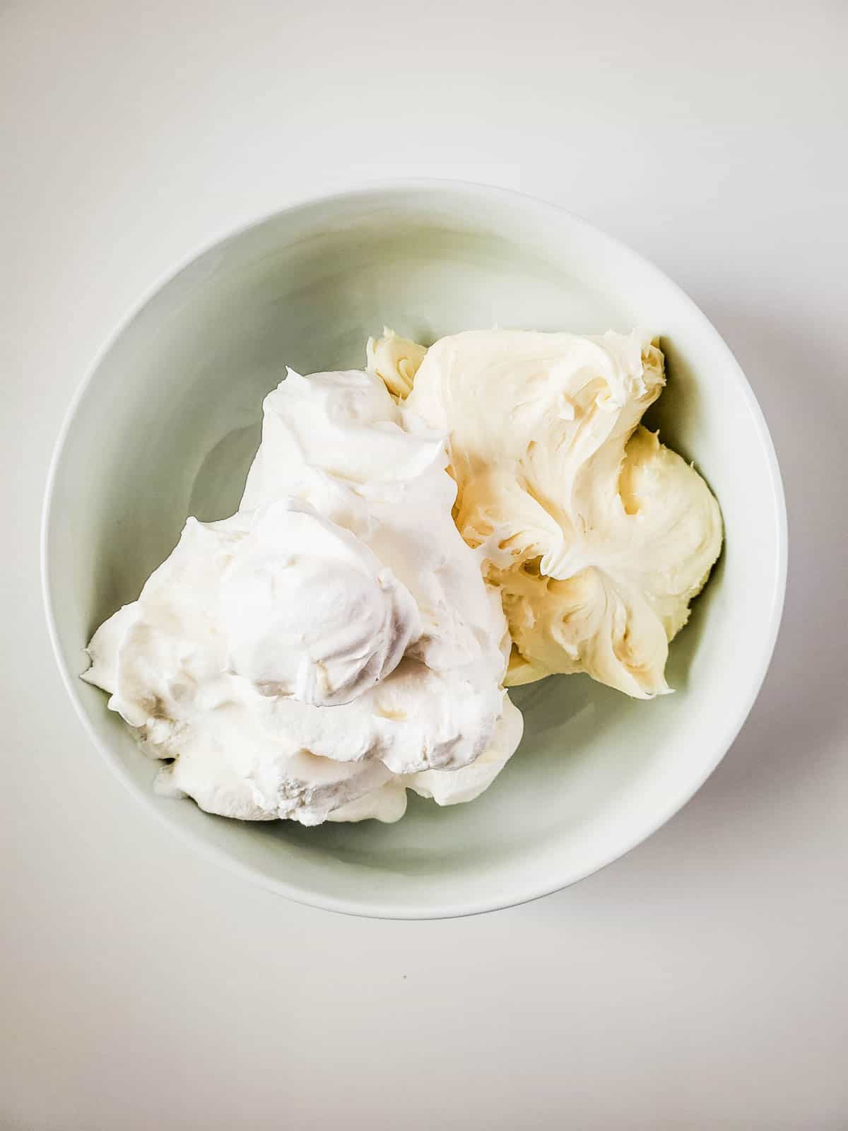 Cool whip and vanilla frosting in a bowl before being mixed.