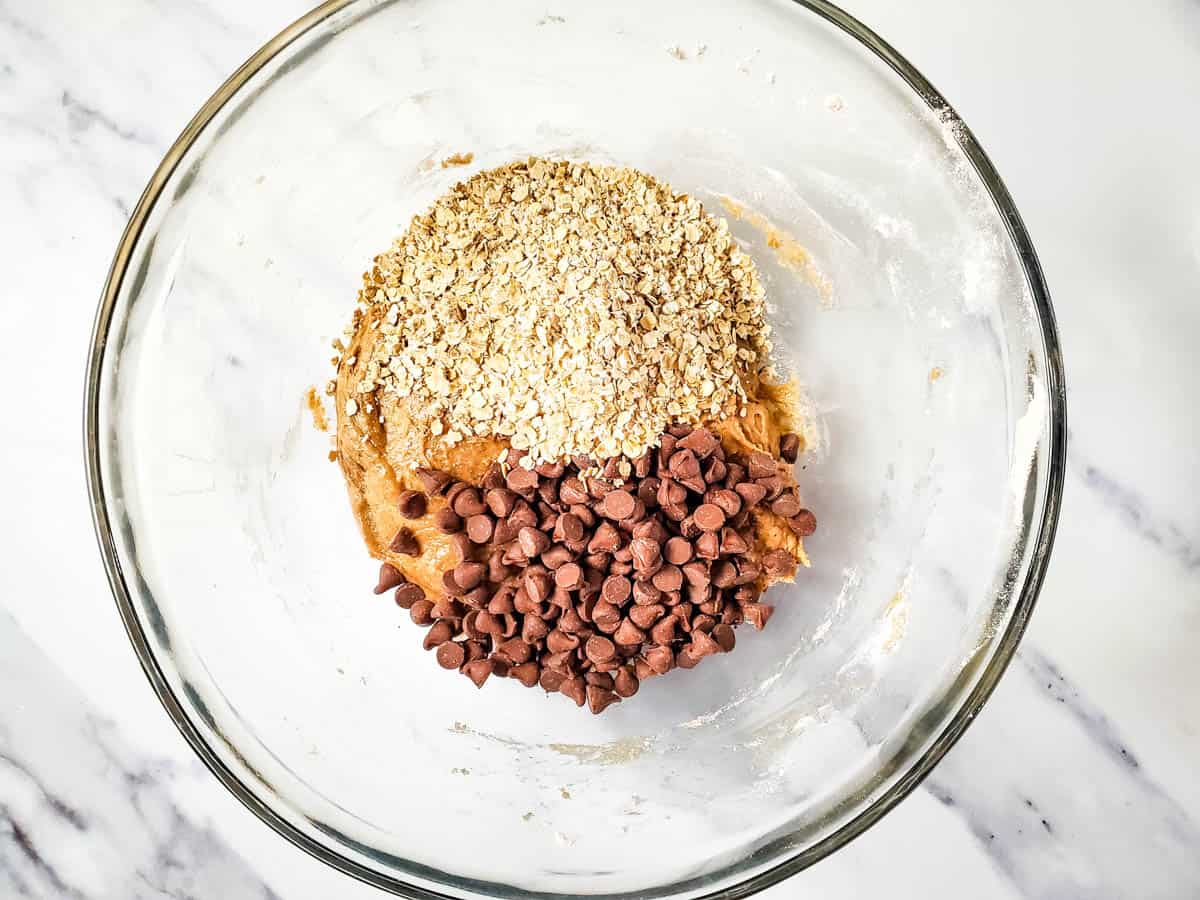 A glass mixing bowl with chocolate chips and dry cake mix to make cookies with.