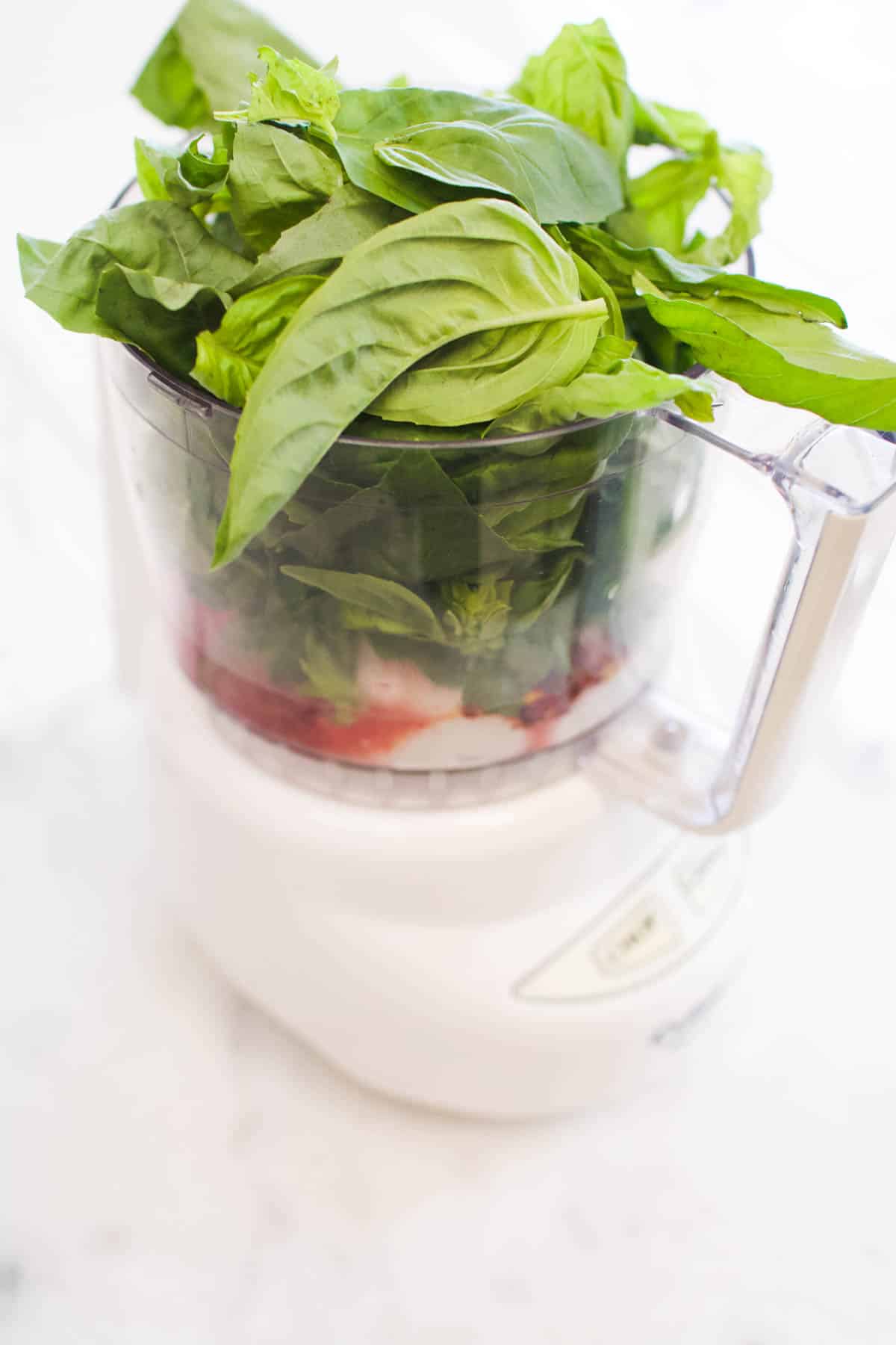 A food processor filled with yogurt, herbs, and spices.