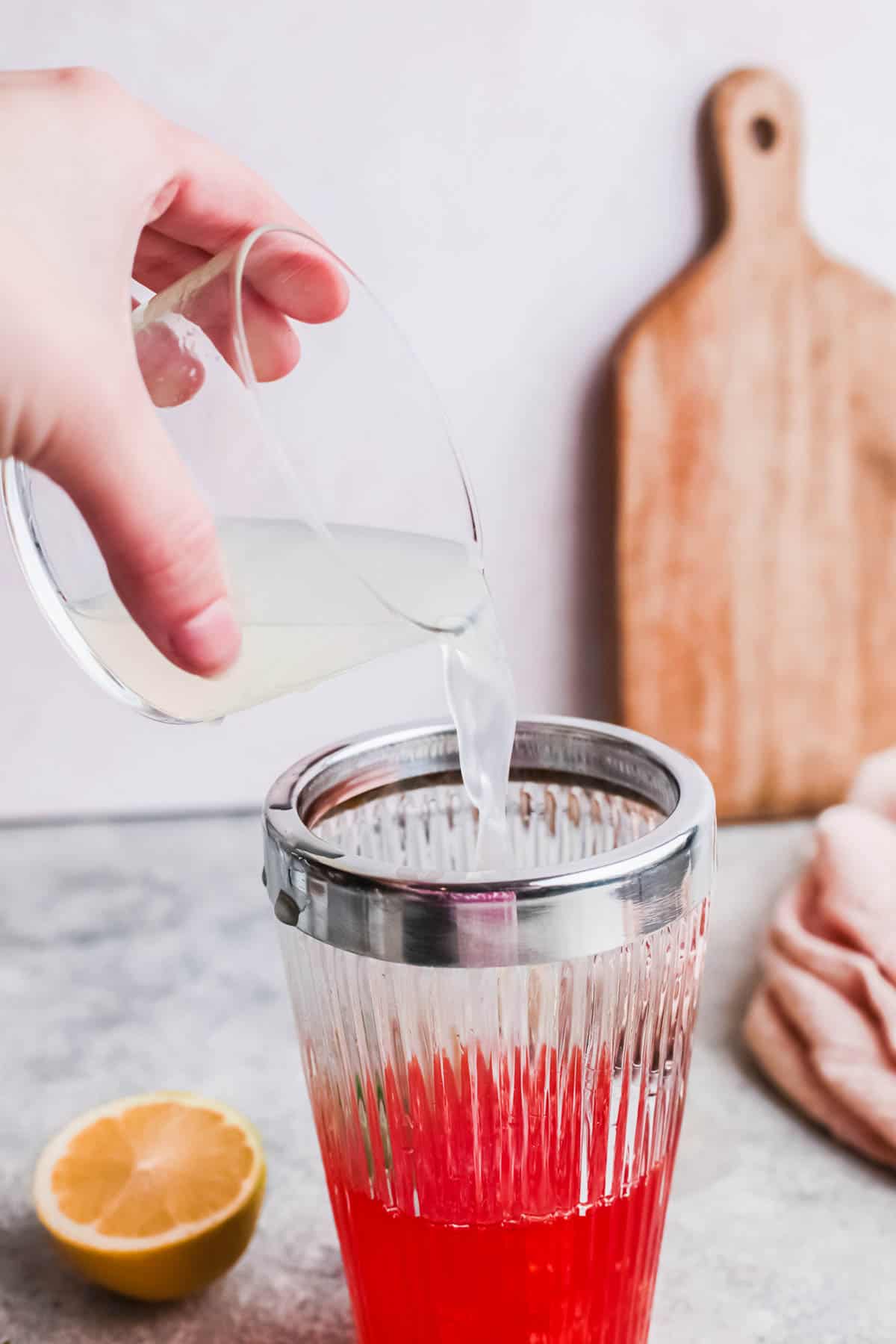 Woman pouring lime juice into a cocktail shaker.