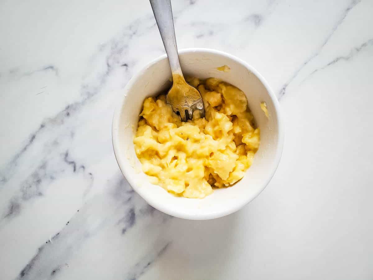 A mashed banana in a small white ramekin.