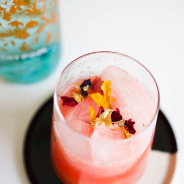 Watermelon juice and gin on the rocks garnished with edible flowers.