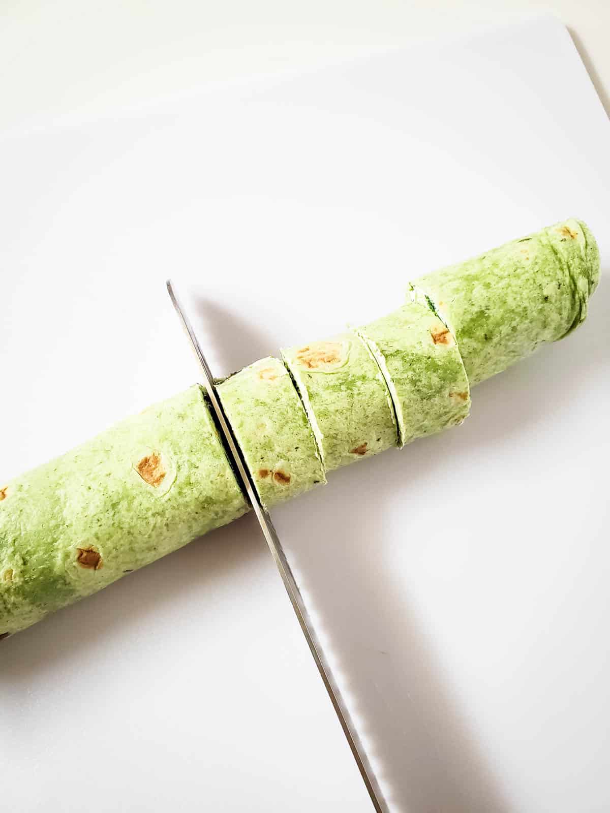 Using a chef's knife to cut the pinwheels.